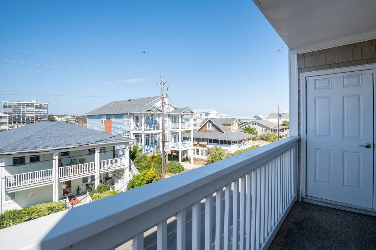 A relaxed balcony scene featuring a railing, nearby houses, and a clear sky—ideal for enjoying morning coffee, sunset drinks, or casual gatherings with friends after a day of island fun.
