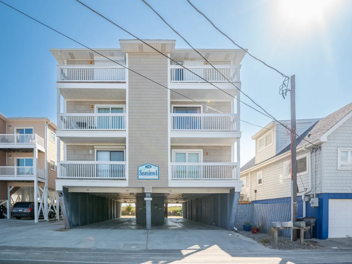 An exterior view of the Sea View condo building, featuring inviting balconies and clear signage. The building is surrounded by palm trees and hints at a welcoming, laid-back beachside atmosphere.